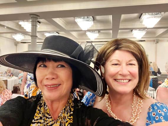 Helen's Hat Tea Party guests enjoyed trying on some of her iconic headgear and then bidding for them at auction. Here's one modelling a stylish black number while former Lord Lieutenant Helen Nellis looks on