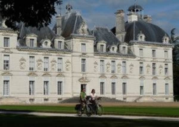 Cyclists passing through Chateau de Cheverny at Cheverny in Loire Valley
