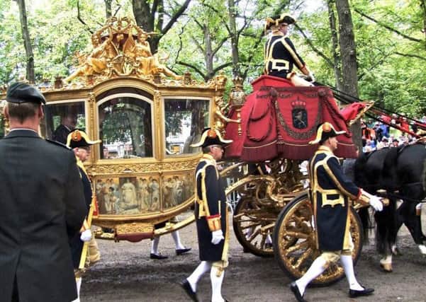 King Willem-Alexander waves to the vast crowds from his golden coach.